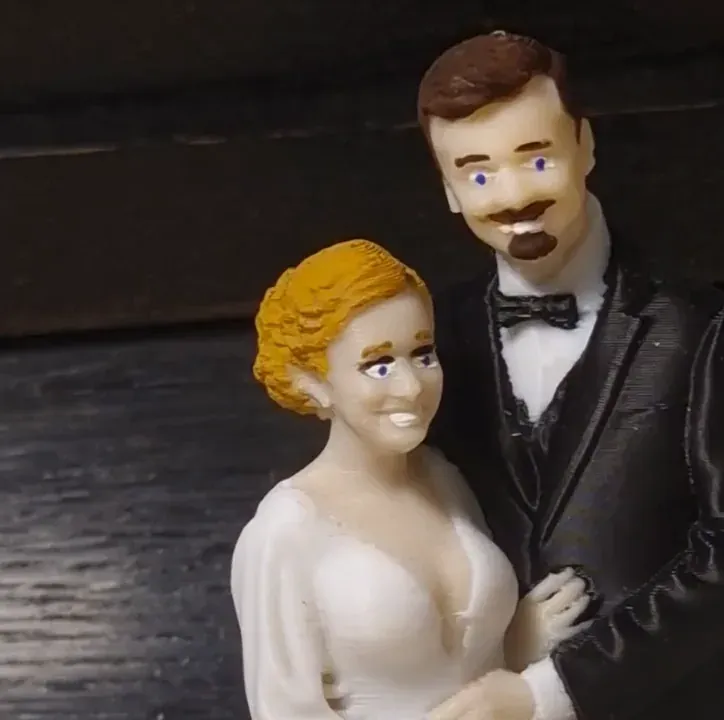 Close-up of a printed bride and groom, with fine horizontal lines across the groom's black suit and the bride's white dress