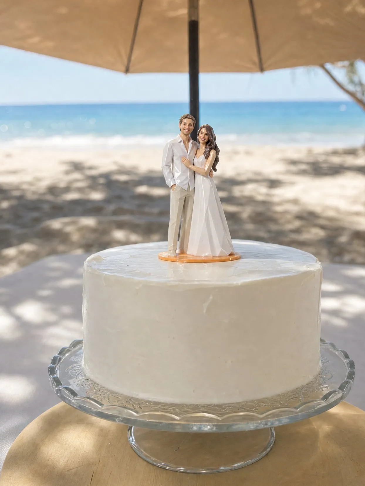 A couple topper on a white cake on a shaded table near the sea