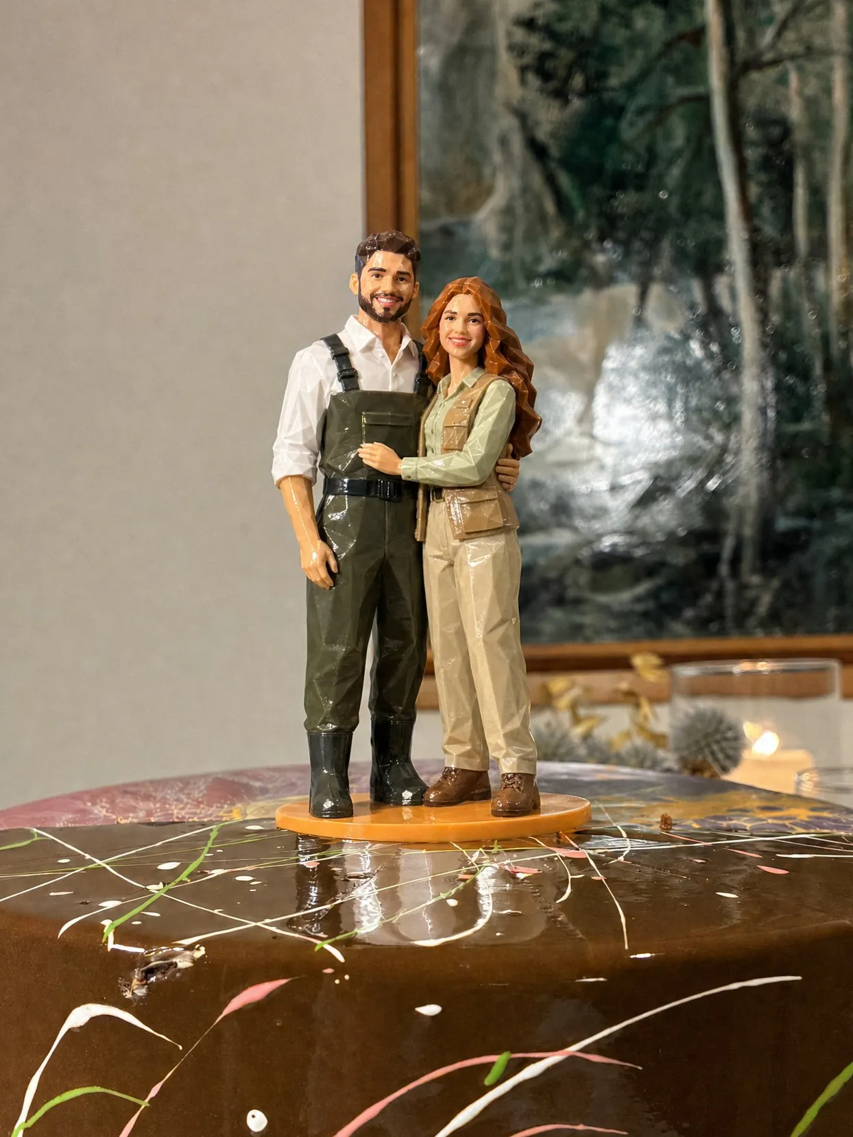 The same topper couple: he in olive waders over a white shirt, she in a tan fishing vest over a sage shirt.