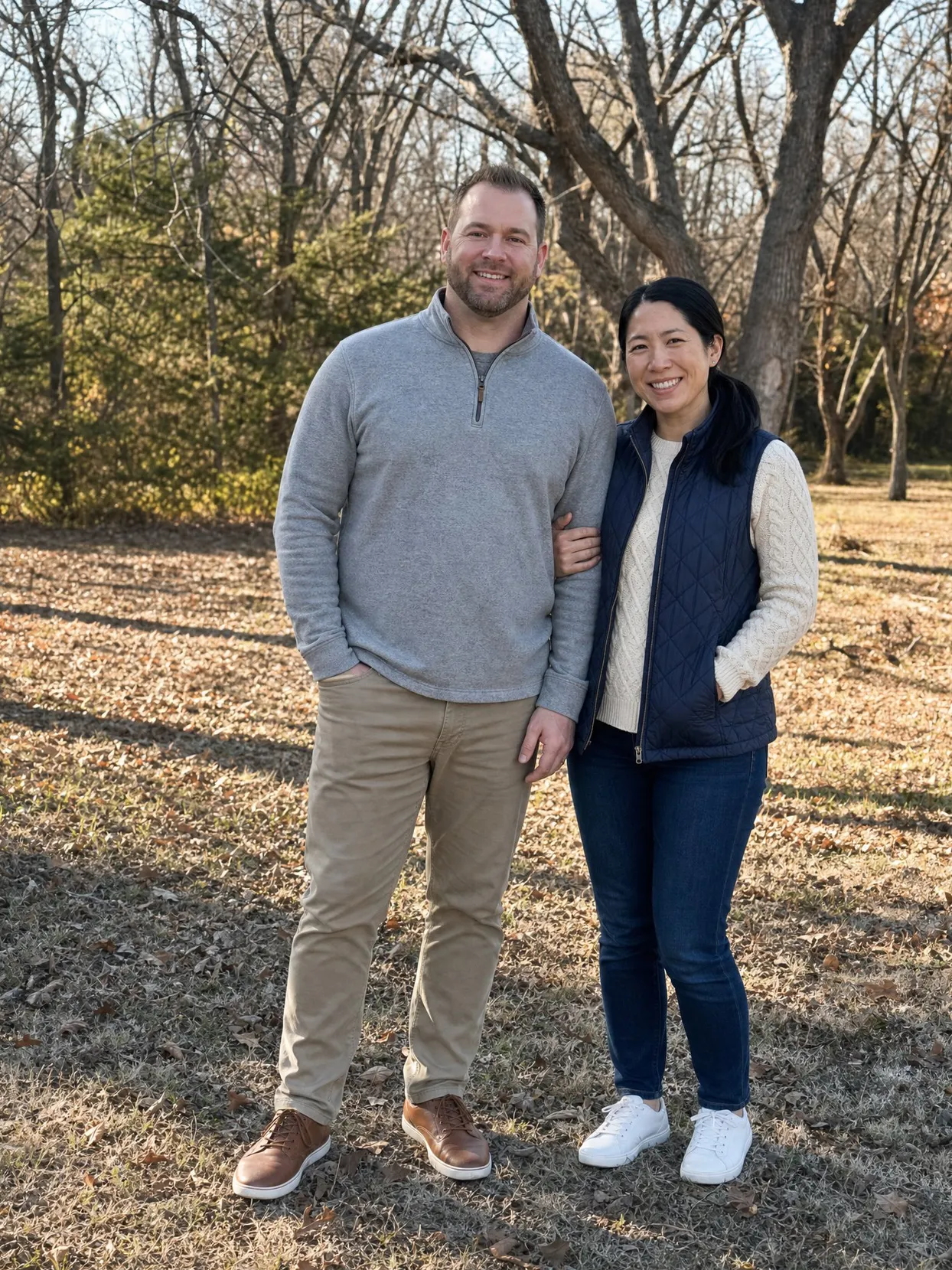 A couple on a winter lawn, he in a gray quarter-zip and khakis, she in a navy quilted vest and a cream sweater.