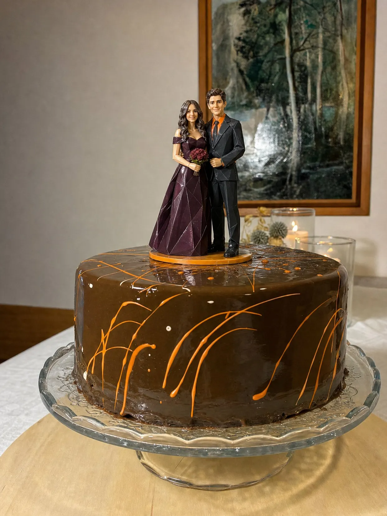 A couple topper, she in a plum gown holding red roses, he in a black suit with an orange shirt, on a chocolate cake with orange drizzle.