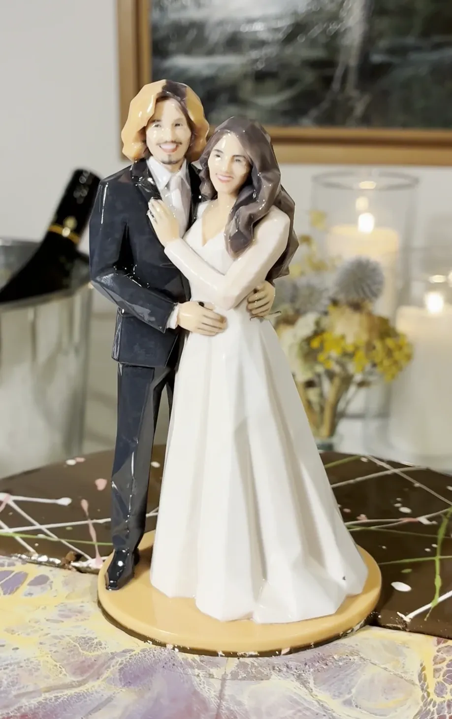 Front view of a printed bride and groom figure on an orange base on a marbled cake top