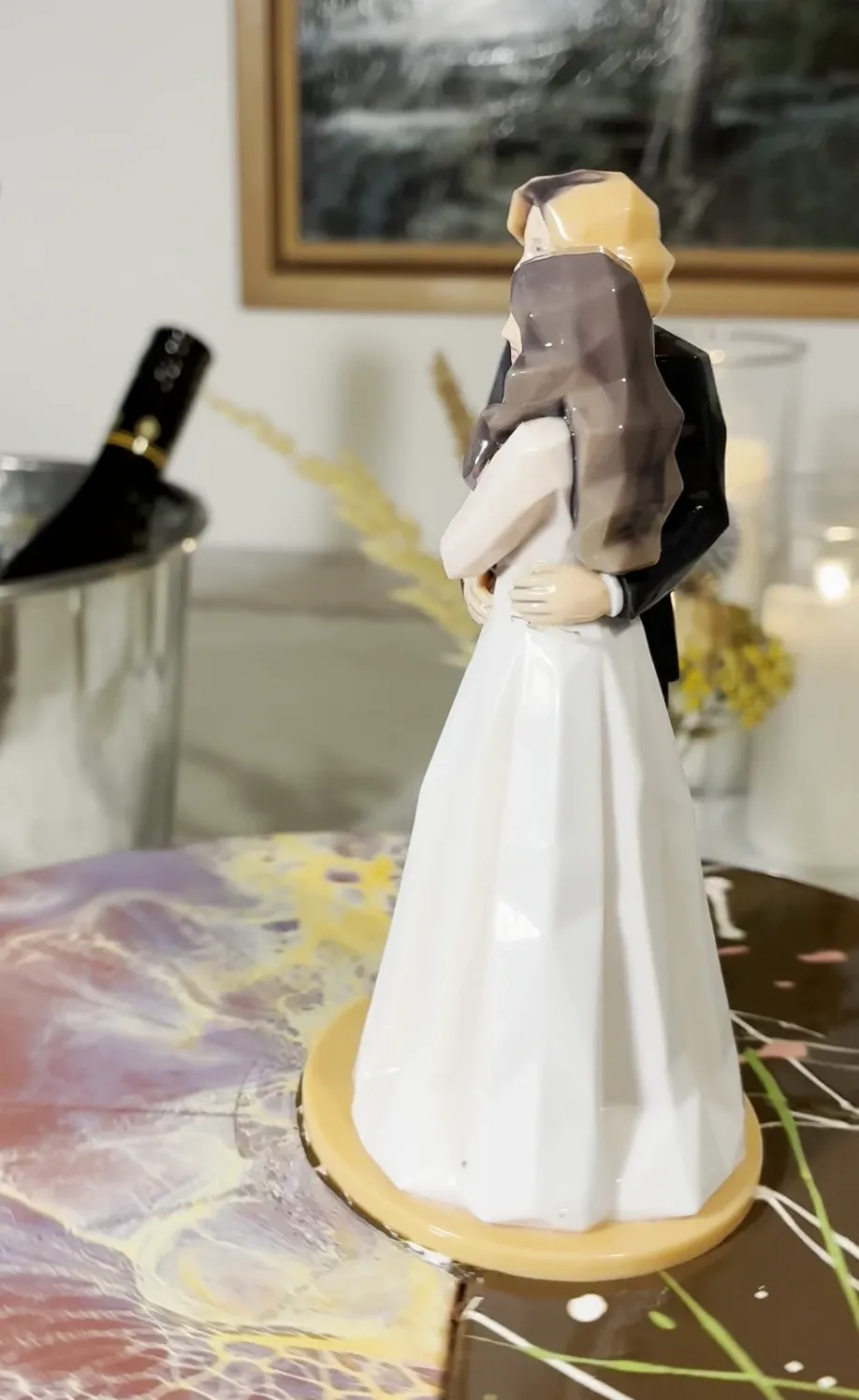 Side view of a printed bride and groom figure on an orange base on a marbled cake top