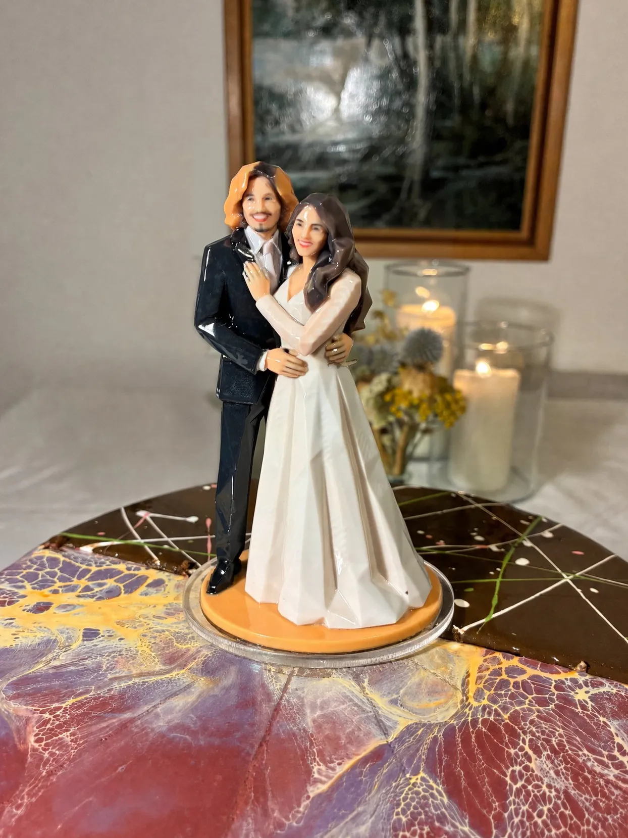 Bride and groom figure on an orange base standing on a clear round disc on a marbled cake top