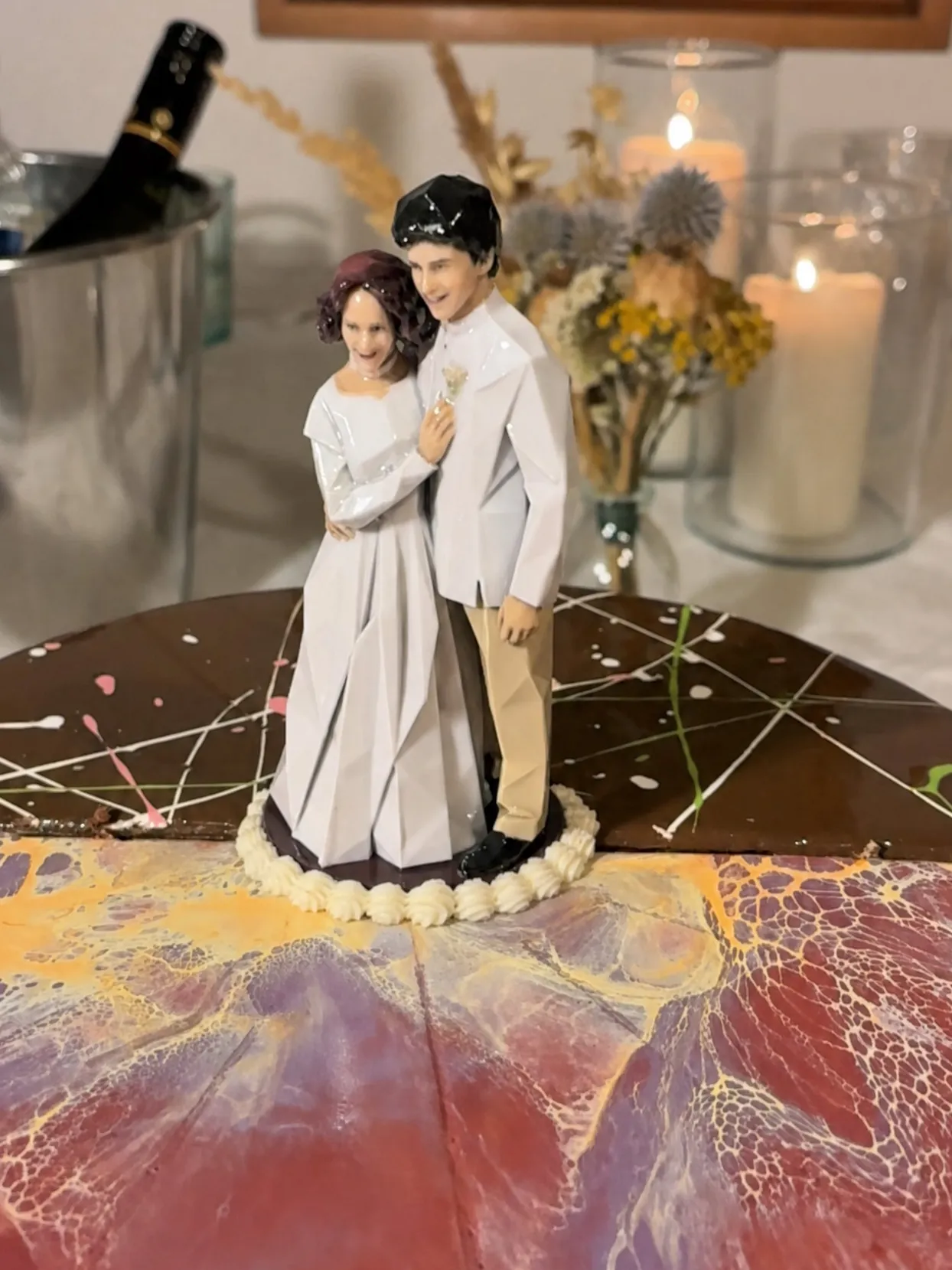 Bride and groom figure with a ring of piped off-white buttercream shells around its base on a cake