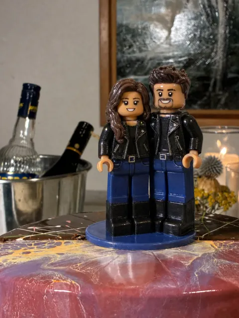 Topper ng couple na naka-itim na leather jacket, jeans at boots sa wedding cake.