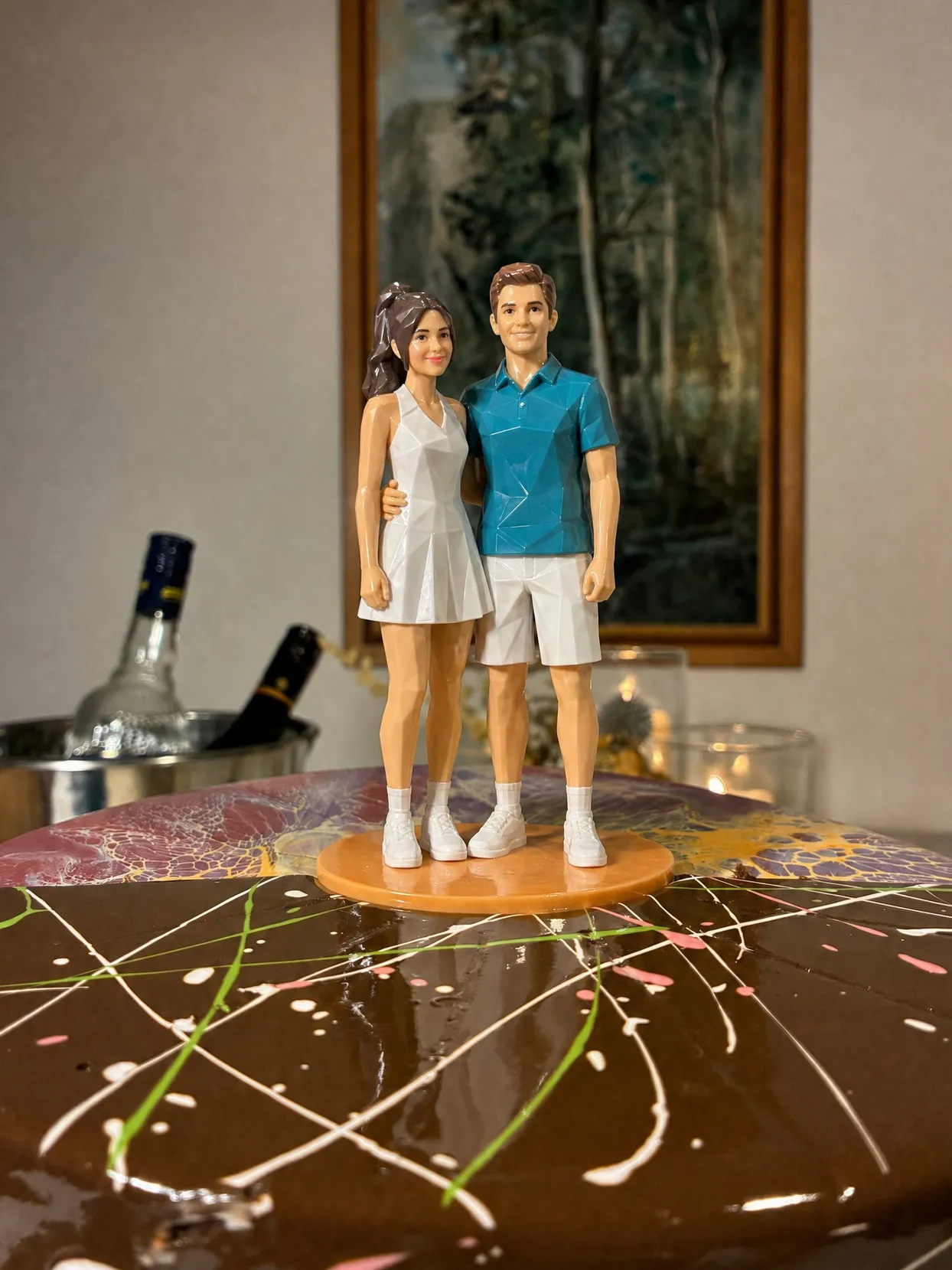 The same topper couple: she in a white tennis dress, he in a teal polo and white shorts.