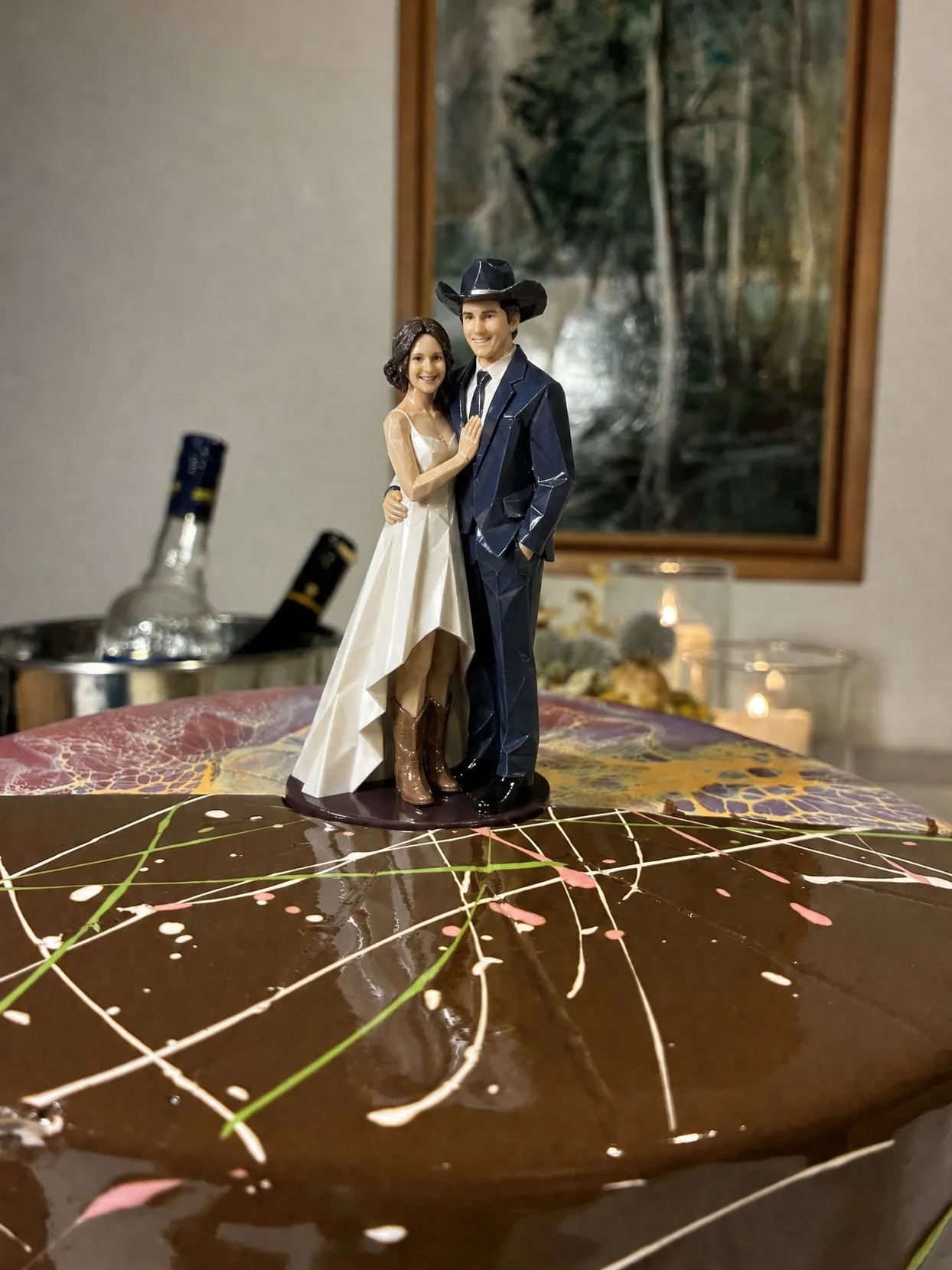 A couple topper, the groom in a navy suit and cowboy hat, the bride in a high-low satin dress and tan cowboy boots, on a chocolate cake.