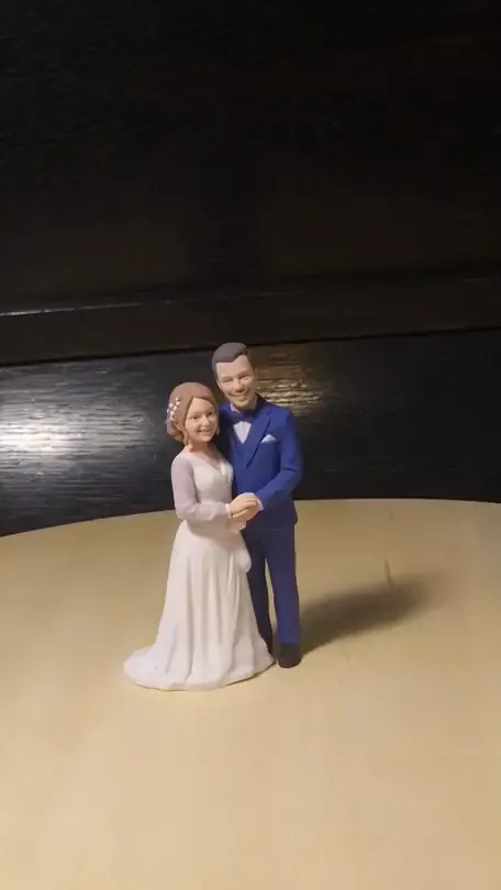 A small printed bride and groom topper, the groom in a blue suit, the bride in a white gown